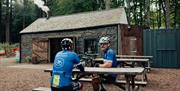 Cyclists on picnic bench seating outside The Coffee Cottage