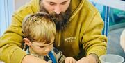 A man helps a a boy to decorate his cupcake