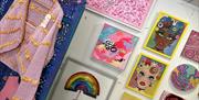 A vibrant display of pop art at Pink Seaweed, bursting with pinks and brights, featuring bold wall pieces and wearable art by local creatives includin