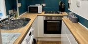 Galley style kitchen with oven, microwave, washer/dryer, fridge and all relevant kitchen accessories