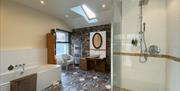 This large and bright bathroom is another focal point of the house. It features a Manx stone wall, a Velux window, a full size bath tub and a large wa