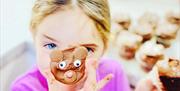 A little girls holds up a Teddy Bear cupcake in front of her face