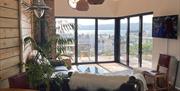 Open plan contemporary living space featuring bifold doors onto sea view deck & cosy log burning stove