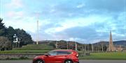Tynwald Hill and the Royal Chapel with the Tour Guide's Car a red coloured Honda CR-V