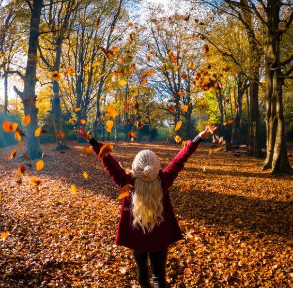 Lady throwing leaves in the air on the Isle of Wight