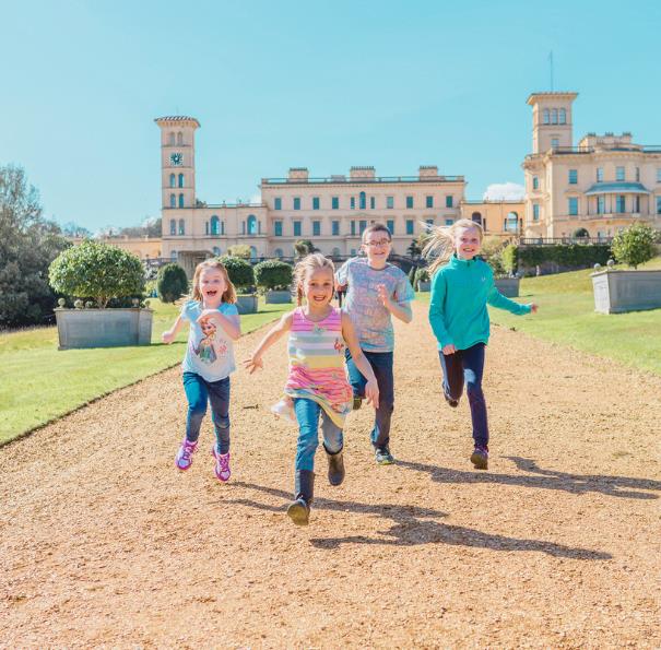Children running in the grounds with Osborne House in the background on the Isle of Wight