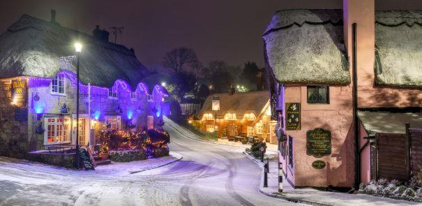 Night-time along Shanklin Old Village with snow, Christmas tree and lights on display on thatched buildings