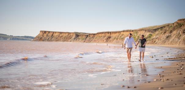 Two men holding hands walking on Compton beach on the Isle of Wight