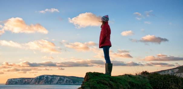 Lady standing on the cliff watching the sun set across the water on the Isle of Wight