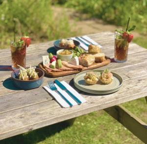 Sharing cheese and bread platter with drinks on a picnic table, Isle of Wight
