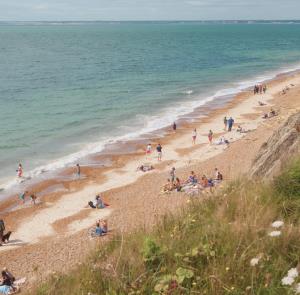 People stilling on the beach and paddling in the sea on a beach on the Isle of Wight