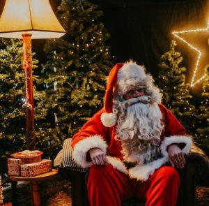 Father Christmas sitting in a chair with festive decorations all around