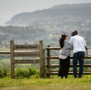 Couple standing on Brading Down looking at the countryside and sea views on the Isle of Wight