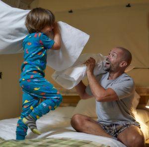 Father and son enjoying a pillow fight in a glamping tent