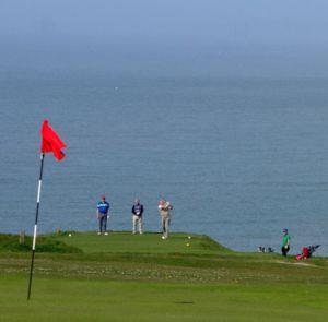 People playing golf on Freshwater Bay Golf Club with the sea behind them on the Isle of Wight