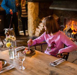 A girl eating in front of a fireplace at a pub on the Isle of Wight