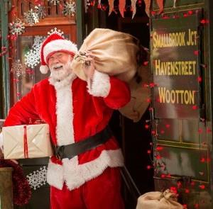 Father Christmas with presents standing next to the train at Isle of Wight Steam Railway
