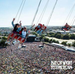 People on a ride at the Isle of Wight Festival with an aerial view of the festival site. 