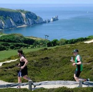 Men running along cliff with the Needles in the background