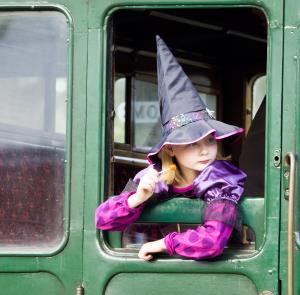 Girl dressed up as a witch looking out the window sitting on the train at the Isle of Wight Steam Railway