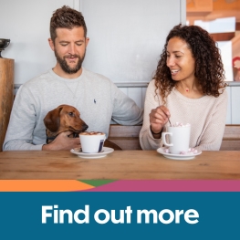 Couple sitting with their dog drinking hot drinks on the Isle of Wight