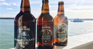 Three bottles of beer on ledge overlooking solent with ferry in background, Isle of Wight, Local Produce, Island Brewery, let's buy local
