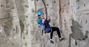 Isle of Wight, Activity, Rock Climbing, Sandown Rocks, young person dangling at height from climbing wall giving thumbs up.