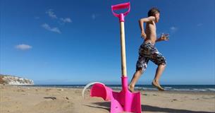 Boy next to bucket and spade on Yaverland Beach, Sandown, Isle of Wight, Things to Do