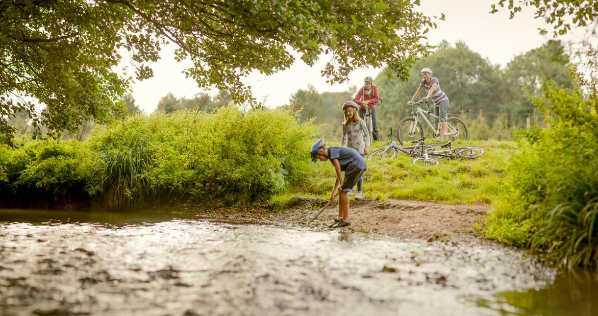 Family on a bike ride playing near the river, Isle of Wight