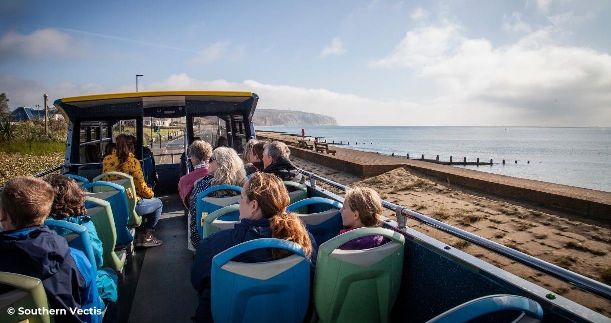 Group of people on the Southern Vectis open top bus travelling along Sandown esplanade on the Isle of Wight