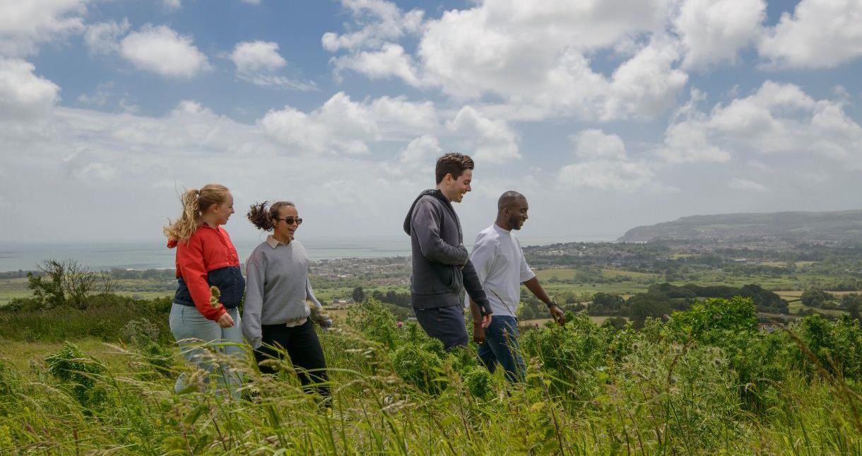 Group of friends walking along the Downs with Sandown and the sea in the background