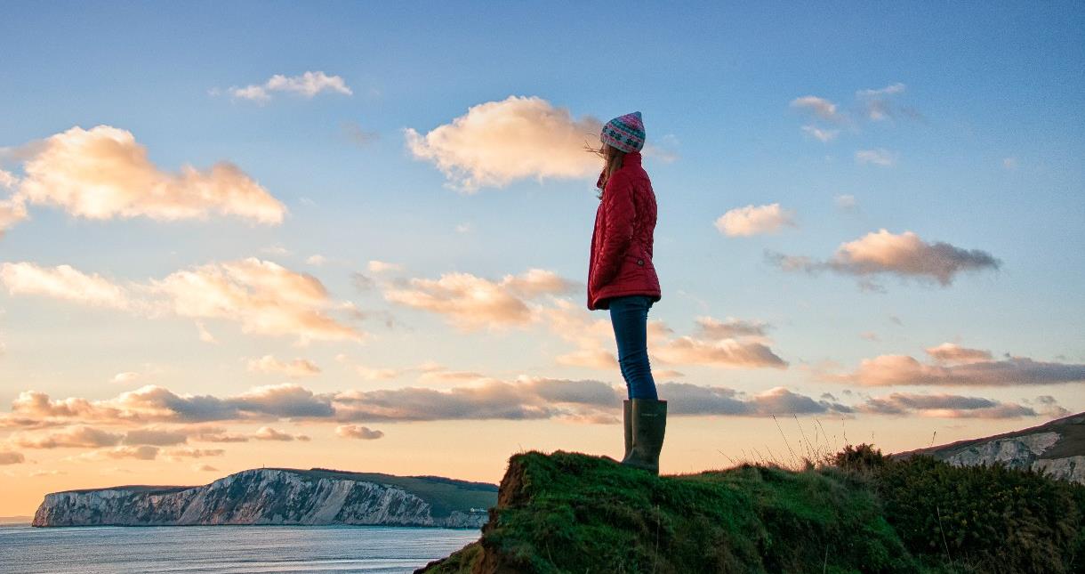 Lady standing on cliff looking out to sea on the Isle of Wight