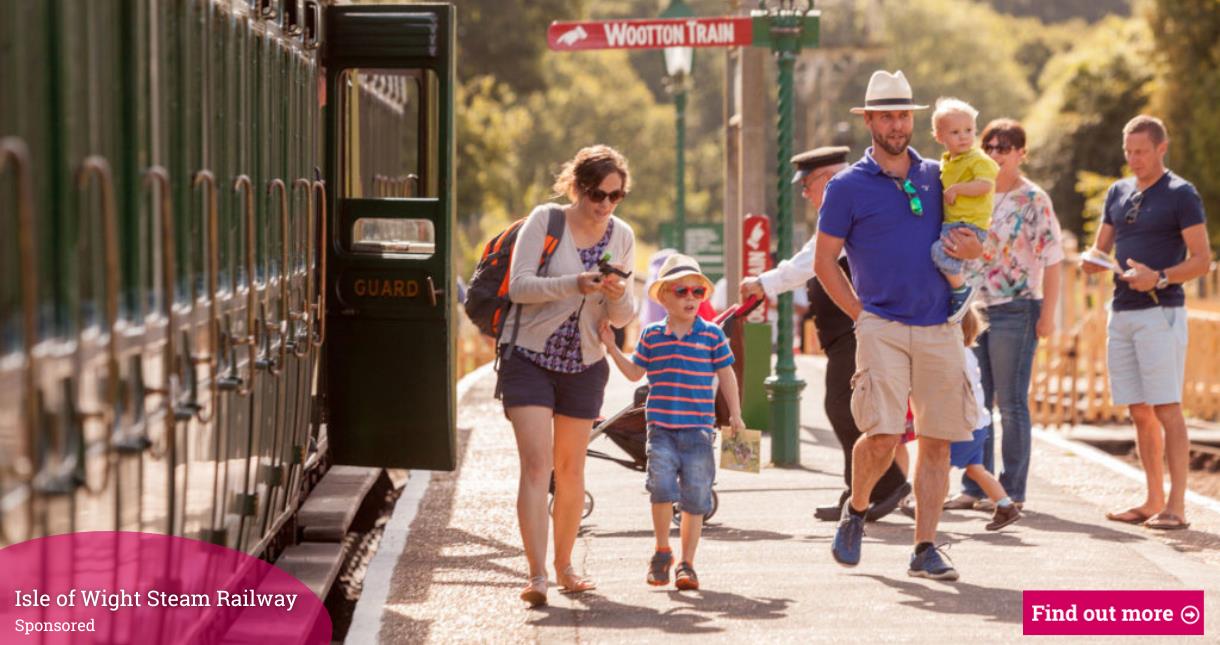 Family on the platform next to a stationary steam train at Isle of Wight Steam Railway