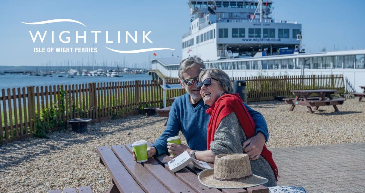 Couple enjoying a coffee sitting on a picnic bench at the Wightlink terminal in Lymington