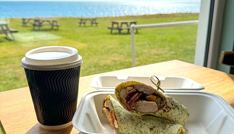 Bacon and sausage wrap with cup of coffee on a table with the sea view in the background, Isle of Wight Pearl, Round the Island Race