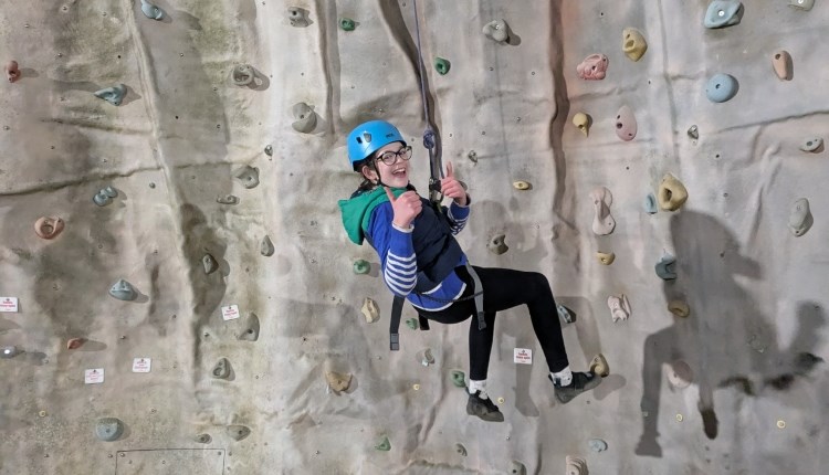 Isle of Wight, Activity, Rock Climbing, Sandown Rocks, young person dangling at height from climbing wall giving thumbs up.
