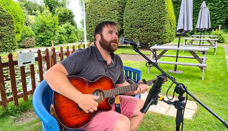 Sean Goodfield playing a guitar in the garden of Luccombe Hall Hotel, Shanklin, Isle of Wight, live music, summer, performance
