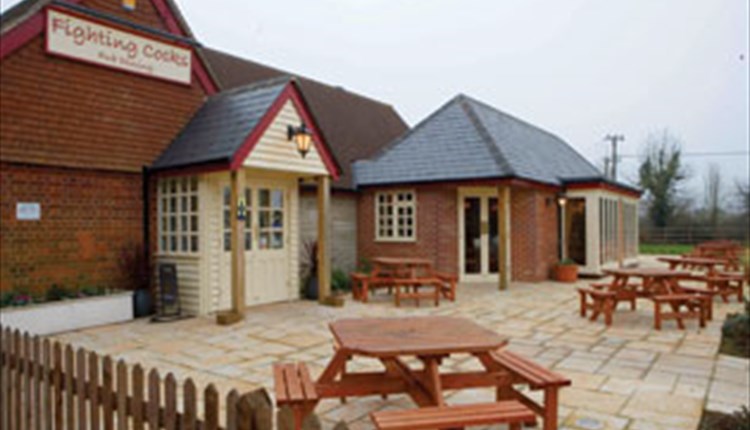 Outside view of The Fighting Cocks with outside eating area, Arreton, pub