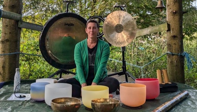 Mel sitting with bowls and gongs to provide a sound bath in the forest on the Isle of Wight, wellness, retreat, activity, health and wellbeing, sanctu