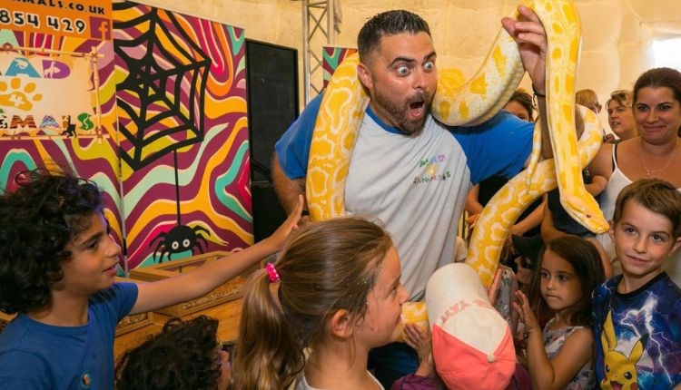 Man holding a large yellow snack whilst children are gathered around watching, Live & Wild Weekend at Tapnell Farm Park, what's on, events, Isle of Wi
