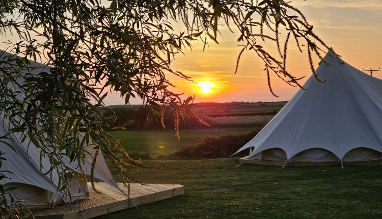 Outside view of bell tents at Warren Hill Camp with sunset in the background, glamping, accommodation, camping, Isle of Wight, family friendly, couple