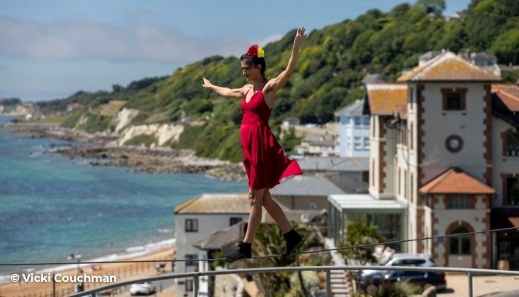 Lady walking along a tightrope with the sea in the background in Ventnor on the Isle of Wight