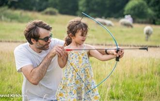 Father helping daughter with archery, National Trust event, Newtown National Nature Reserve, events, what's on, Isle of Wight - photo credit: David Ki