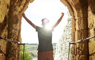 Man standing in arch of Carisbrooke Castle looking at the view, historic attraction, family fun, children's activities, summer event, what's on, Isle