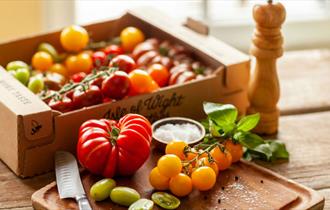 Tomatoes produced by The Tomato Stall on a chopping board and various types of tomatoes in a box, local produce, Isle of Wight, let's buy local