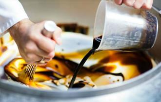Person making Minghella ice cream with chocolate sauce in a large mixing bowl, local producers, Isle of Wight, local produce, let's buy local