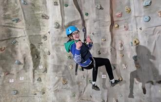Isle of Wight, Activity, Rock Climbing, Sandown Rocks, young person dangling at height from climbing wall giving thumbs up.