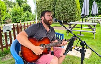 Sean Goodfield playing a guitar in the garden of Luccombe Hall Hotel, Shanklin, Isle of Wight, live music, summer, performance