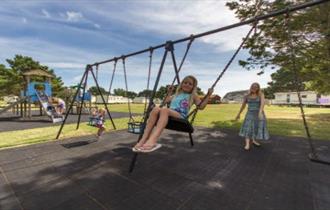 Child on the swing at the playground at Sandhills Holiday Park, Bembridge, Isle of Wight