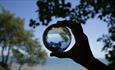 Person holding view of sea from Shanklin Chine through a large glass marble, Things to Do, Isle of Wight